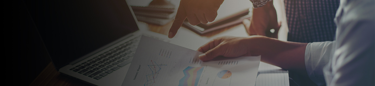 Person analyzing financial charts with laptop in background